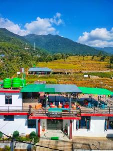 a building with a green roof with mountains in the background at Raahi Stay, Landing site Bir - Stay & Cafe in Bīr