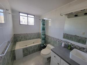 y baño con bañera, aseo y lavamanos. en BELLAVISTA REST, en Quito