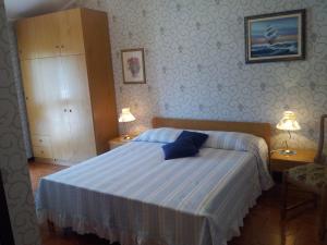 a bedroom with a bed with blue sheets and two lamps at Meublè Al Ponte in Grado