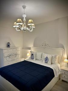 a white bedroom with a blue and white bed with a chandelier at Maison Mele Ischia in Ischia