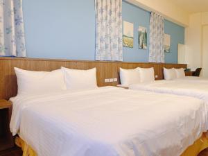 two beds in a hotel room with white sheets at 漫活時光民宿 Leisure Living in Baisha