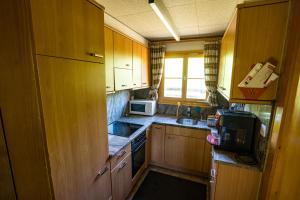 uma pequena cozinha com armários de madeira e um micro-ondas em Haus Chalet Beverin em Cazis