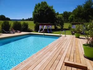 a swimming pool with a wooden deck and a swimming pool at La maison de gilbert in Chaudes-Aigues