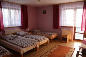 a room with three beds and windows with red curtains at Pokoje Gościnne Łukaszczyk in Zakopane