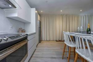 cocina con fogones y mesa con sillas en Commandeurs Apartments unit 4D, en Oranjestad