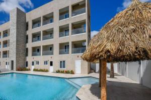 un gran edificio con piscina y sombrilla de paja en Commandeurs Apartments unit 4D, en Oranjestad