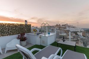 a balcony with white chairs and a view of a city at Dimora Matteotti by Meravigliosa Puglia RealEstate in Ostuni