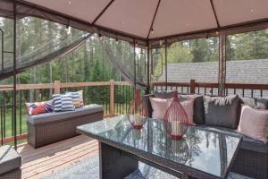 a patio with a couch and a glass table at Chalet SPA SAUNA Tremblant in Saint-Faustin