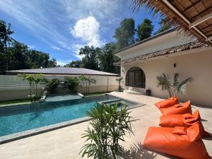 a swimming pool with orange pillows next to a house at Private pool villa in Thongsala