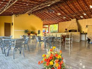 瓜拉雷馬的住宿－Chacara com Wi-Fi e muito lazer em Guararema SP，一间带桌椅和鲜花的用餐室