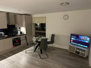 a kitchen and a dining room with a table and a television at Kensington House by MNK Estates in Slough