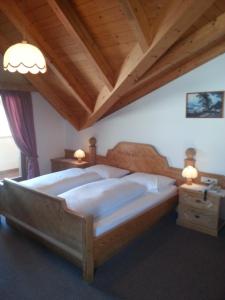 a bedroom with a large bed and a wooden ceiling at Pension Panorama in Monguelfo