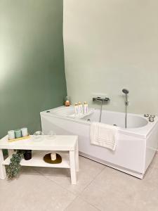 a white bathroom with a tub and a table at CARMA SUITE in Naples