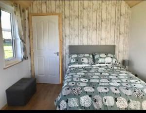 1 dormitorio con cama, ventana y puerta en The Snuggly Sheep Farm Stay Shepherd Hut, en Ballyshannon