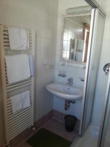 uma casa de banho branca com um lavatório e um espelho em Pension Panorama em Monguelfo