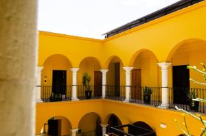 a yellow building with columns and a balcony at Hotel Casona Oaxaca in Oaxaca City