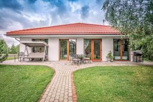 a small white house with a patio and grass at Župė De Lux in Radailiai