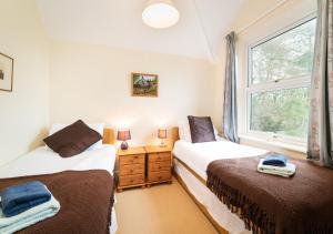 two beds in a room with a window at Knowles in Colyton