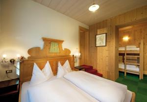 um quarto com uma cama branca e uma cabeceira em madeira em Residence Adler em Villabassa