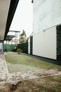 Casa Tipo Loft- Tigre Centro في تيغري: جدار أبيض بجانب مبنى به ساحة