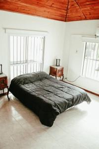 Casa Tipo Loft- Tigre Centro في تيغري: سرير في غرفة بيضاء مع نافذتين