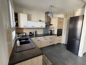 a kitchen with a sink and a refrigerator at Superbe appartement avec parking in La Rochelle
