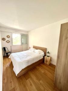 a bedroom with a large bed with a wooden floor at Superbe appartement avec parking in La Rochelle