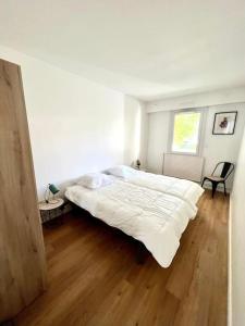 a bedroom with a large white bed and a wooden floor at Superbe appartement avec parking in La Rochelle