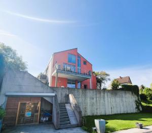 a red building behind a concrete wall with a staircase at Mountains and Lakes - Villa Gaumberg in Linz