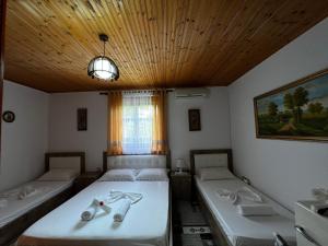 two twin beds in a room with a wooden ceiling at Guesthouse Emiljano in Berat