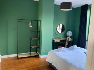 1 dormitorio con paredes verdes, 1 cama y escritorio en Rue Haute by M&M 4 sterren bed en breakfast vlakbij Maastricht, en Eben-Emael