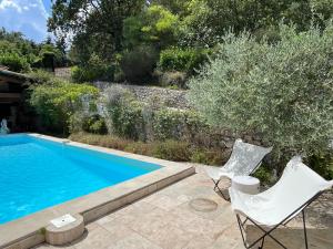 a swimming pool with two white chairs next to a wall at Villa Barelli in Cabris