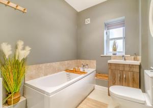 a bathroom with a tub and a toilet and a sink at The Old Post Office in Bentley