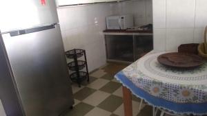 a small kitchen with a table and a refrigerator at Casa para finais de semana temporada in Caraguatatuba