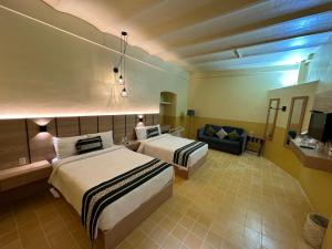 a hotel room with two beds and a couch at Hotel Casona Oaxaca in Oaxaca City