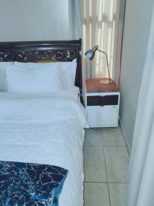 a bedroom with a bed and a lamp on a table at ChoosersExpressHotel in Centurion