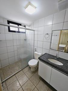 La salle de bains est pourvue de toilettes, d'un lavabo et d'un miroir. dans l'établissement Apartamento Aquaville Resort by WL Temporada, à Aquiraz