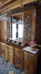 een houten dressoir met een spiegel en een mand met bloemen bij Gulbahaar Group Of HouseBoats in Srinagar
