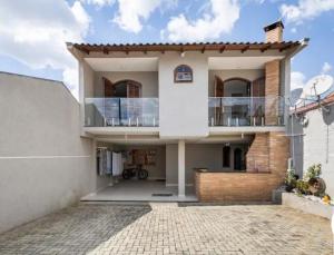 een groot wit huis met een balkon bij Chalé aconchegante próximo ao aeroporto in São José dos Pinhais