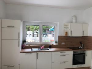 cocina con armarios blancos, fregadero y ventana en Schöne Wohnung in Schwaigern en Schwaigern