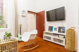 een woonkamer met een witte stoel en een televisie bij Duplex en plein centre historique Aix en provence in Aix-en-Provence