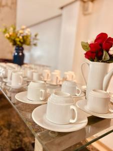 un grupo de tazas y platillos sobre una mesa con rosas en HOTEL CAMPO GRANDE, en Campo Grande