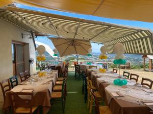 a row of tables with chairs and an umbrella at Lo Scoiattolo Country House in Montorio al Vomano