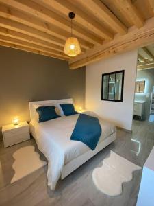 1 dormitorio con 1 cama grande con almohadas azules en La Ferme du Maillot, en Champeau