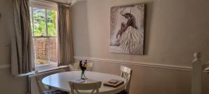 a dining room with a table and a picture of a woman at Millstream House in Winchester