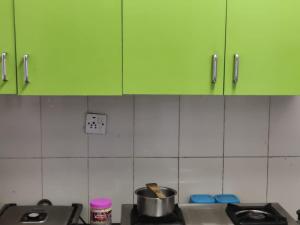 a kitchen with green cabinets and a pot on a stove at Aayushman Homes in Bangalore