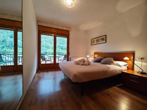 um quarto com uma cama grande, pisos em madeira e janelas em Allotjaments Bruc em Camprodon