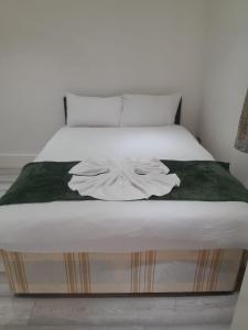ロンドンにあるW3 Guest Houseのベッドルーム(白いベッド、緑の毛布付)