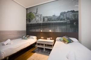 two beds in a room with a picture on the wall at Volantin Apartment in Bilbao