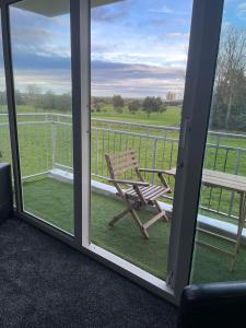 a rocking chair on a porch with a view of a field at 3 Bedroom Apartment with Golf Course View in Newcastle upon Tyne